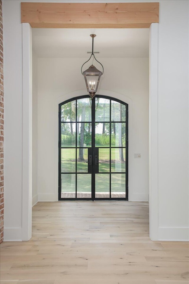 doorway to outside featuring light hardwood / wood-style flooring, french doors, and an inviting chandelier