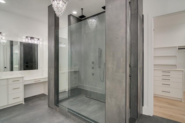 bathroom with a notable chandelier, vanity, and a shower with door