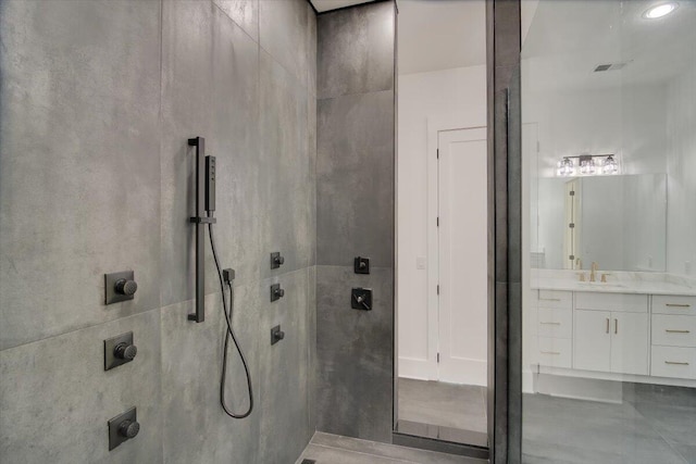 bathroom with a tile shower and vanity