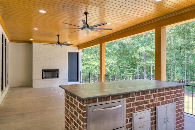 view of patio / terrace with exterior bar, an outdoor brick fireplace, and ceiling fan