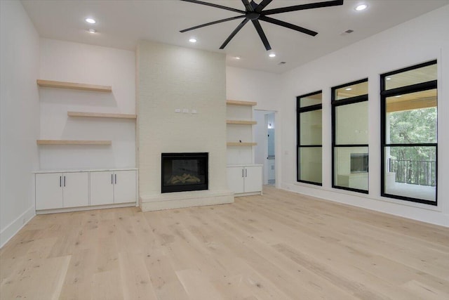 unfurnished living room featuring ceiling fan, light hardwood / wood-style flooring, and a brick fireplace