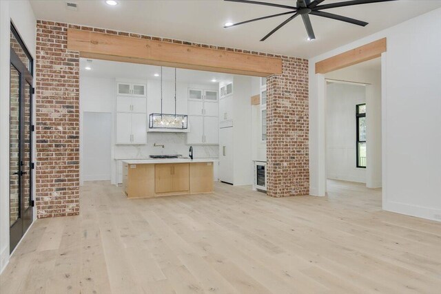 unfurnished living room featuring ceiling fan, light hardwood / wood-style flooring, and brick wall