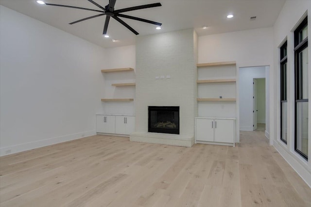 unfurnished living room featuring a fireplace, light wood-type flooring, and ceiling fan