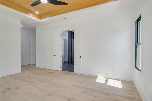 spare room with ceiling fan, wood ceiling, a tray ceiling, and light hardwood / wood-style flooring