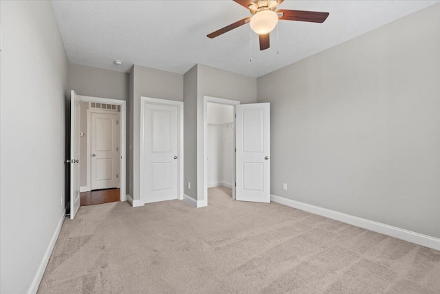 unfurnished bedroom featuring ceiling fan, a closet, light carpet, and a spacious closet