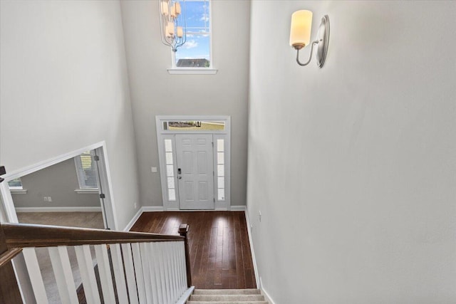 foyer with a towering ceiling, a chandelier, and dark hardwood / wood-style floors