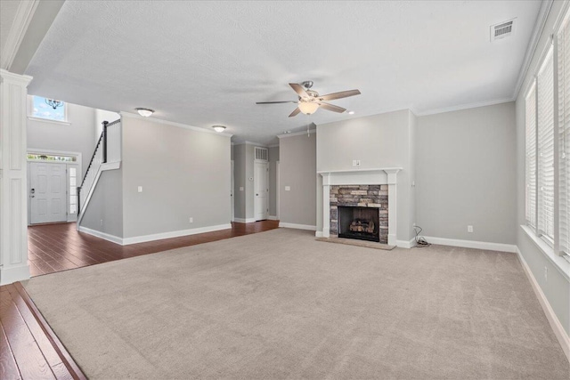 unfurnished living room featuring a fireplace, carpet flooring, ceiling fan, and crown molding