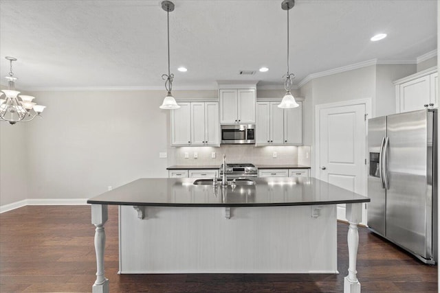 kitchen with pendant lighting, white cabinetry, stainless steel appliances, and an island with sink