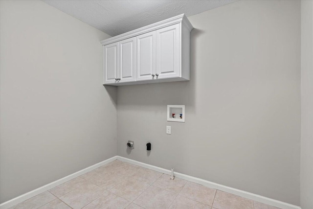 laundry room with cabinets, light tile patterned floors, a textured ceiling, and hookup for a washing machine