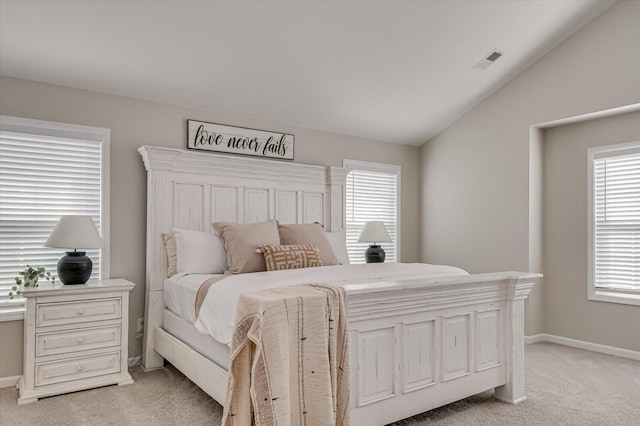 bedroom with lofted ceiling, multiple windows, light colored carpet, and visible vents