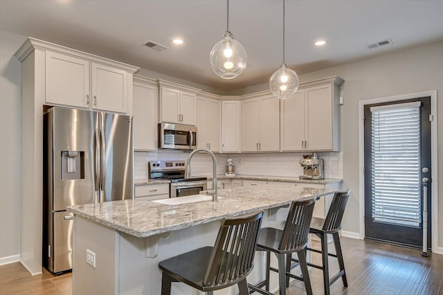 kitchen featuring stainless steel appliances, tasteful backsplash, visible vents, and dark wood finished floors