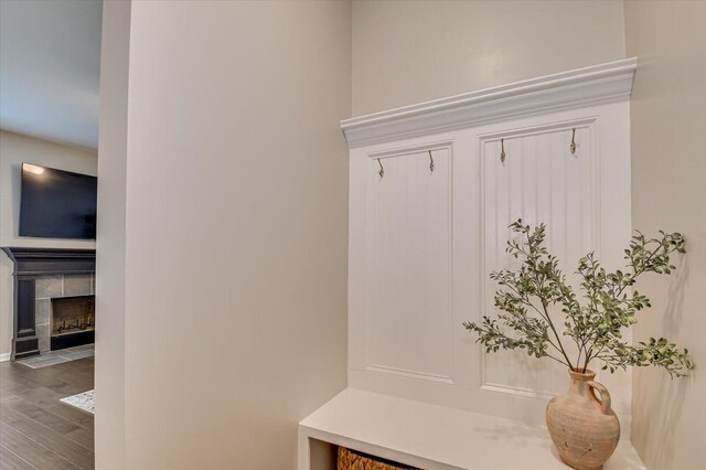 mudroom with wood finished floors and a tile fireplace