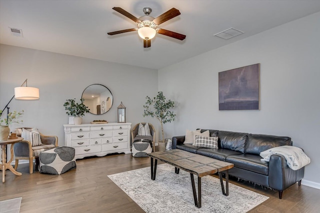 living area with visible vents, a ceiling fan, and wood finished floors