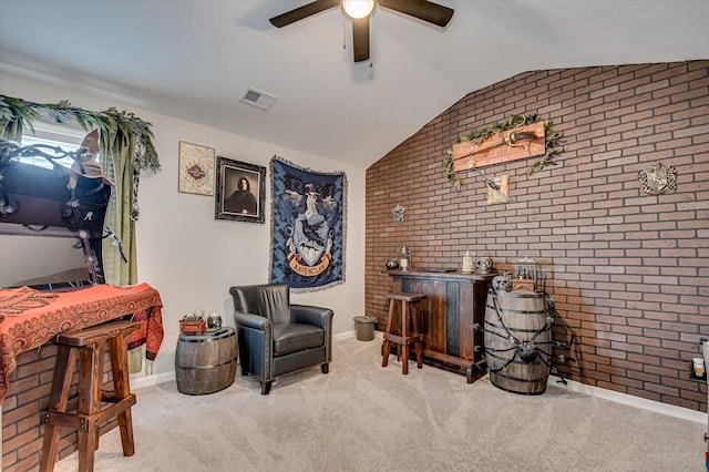 sitting room with visible vents, brick wall, carpet, lofted ceiling, and a ceiling fan