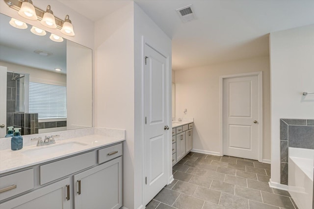 full bath featuring visible vents, two vanities, a sink, tiled shower, and a bath