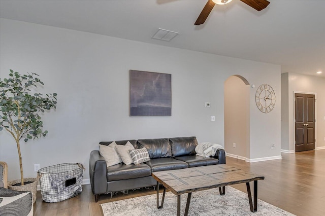 living room featuring visible vents, baseboards, ceiling fan, wood finished floors, and arched walkways