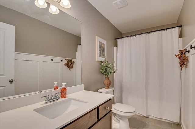 bathroom with tile patterned flooring, visible vents, toilet, a decorative wall, and vanity