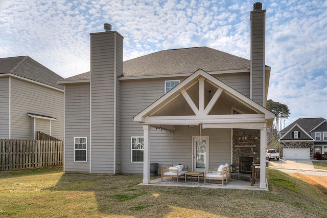 back of property with a shingled roof, fence, a lawn, a chimney, and a patio