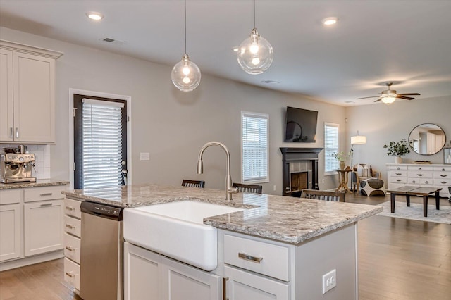 kitchen featuring visible vents, stainless steel dishwasher, light wood-style floors, a ceiling fan, and a sink