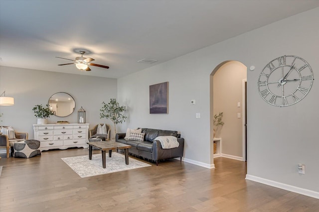 living room featuring visible vents, baseboards, ceiling fan, wood finished floors, and arched walkways