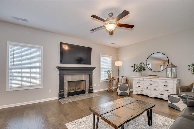 living area with a wealth of natural light, visible vents, a ceiling fan, and hardwood / wood-style flooring