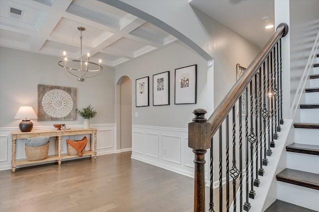 stairway featuring visible vents, beamed ceiling, wood finished floors, arched walkways, and an inviting chandelier