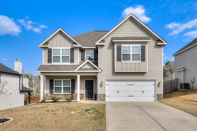 craftsman-style house featuring stone siding, board and batten siding, driveway, and fence