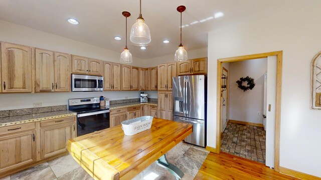 kitchen featuring stainless steel appliances, light brown cabinetry, dark stone countertops, and decorative light fixtures