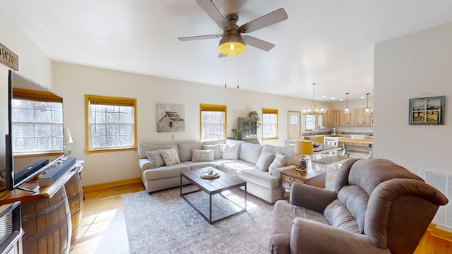 living room with ceiling fan with notable chandelier