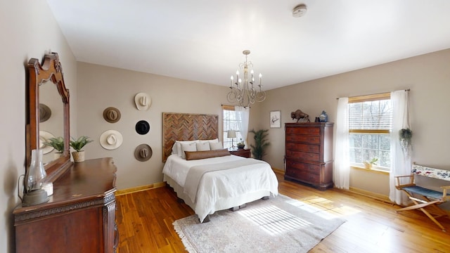 bedroom with a notable chandelier, wood-type flooring, and multiple windows