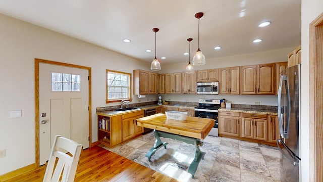 kitchen with hanging light fixtures, light wood-type flooring, appliances with stainless steel finishes, and light stone counters