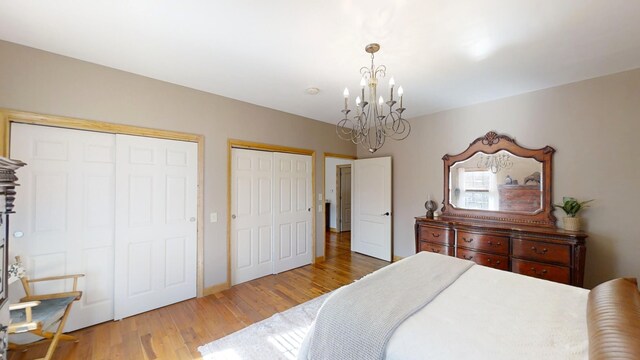 bedroom featuring multiple closets, a notable chandelier, and hardwood / wood-style flooring