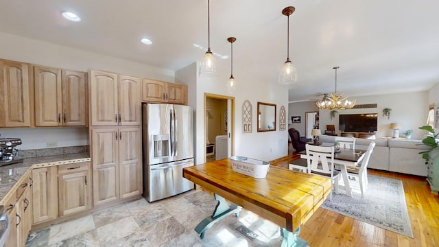 kitchen with pendant lighting, dark stone countertops, light brown cabinetry, an inviting chandelier, and stainless steel fridge