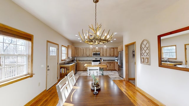 dining area with light wood-type flooring, a chandelier, and sink