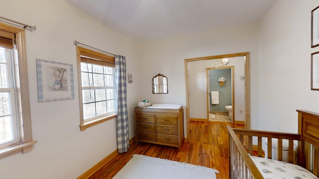 bedroom with multiple windows, connected bathroom, and light wood-type flooring