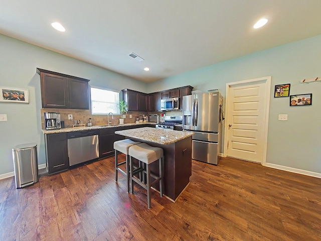 4706 Southwind Rd, Evans, GA 30809 - kitchen featuring appliances with stainless steel finishes, decorative backsplash, dark brown cabinets, dark wood-style floors, and a kitchen island