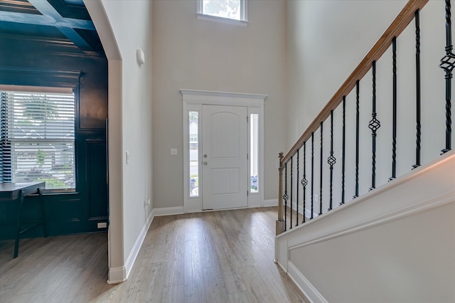 entrance foyer with wood finished floors, stairs, a towering ceiling, and baseboards