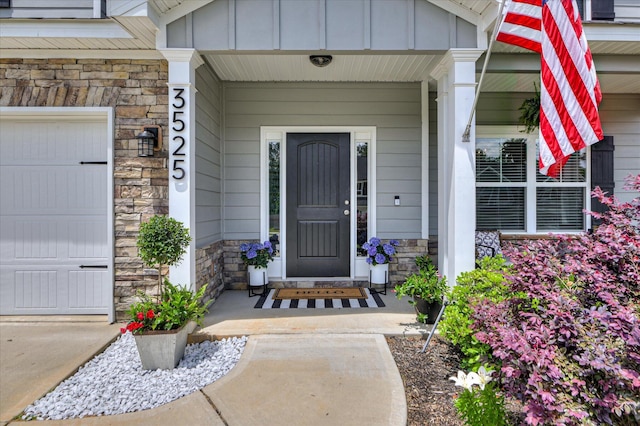 entrance to property with stone siding, a porch, and board and batten siding