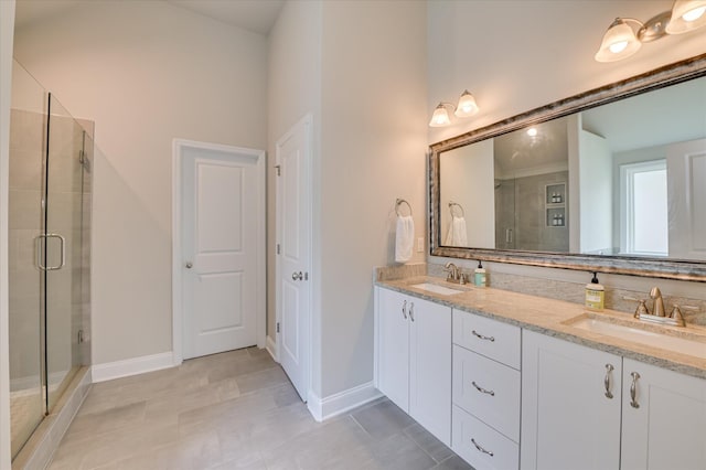 bathroom with a shower stall, double vanity, baseboards, and tile patterned flooring