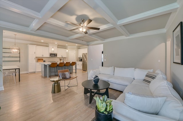 living area with beamed ceiling, a ceiling fan, light wood-type flooring, coffered ceiling, and baseboards
