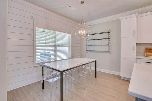 dining room with a chandelier, ornamental molding, light wood-style flooring, and baseboards