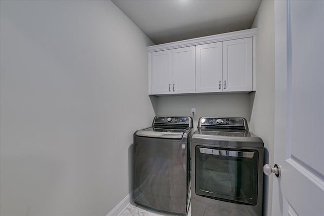 laundry area with light marble finish floors, washer and dryer, cabinet space, and baseboards
