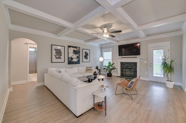 living area with a stone fireplace, baseboards, light wood-style floors, beam ceiling, and coffered ceiling