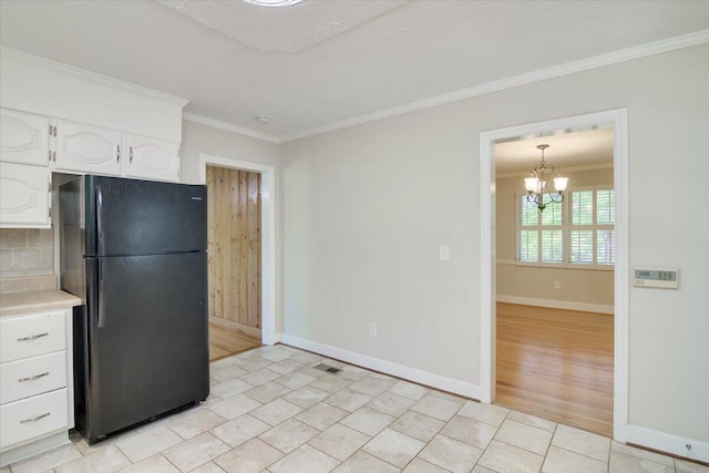 427 Ashland Dr, Augusta, GA 30909 - kitchen with freestanding refrigerator, ornamental molding, white cabinetry, a chandelier, and light countertops