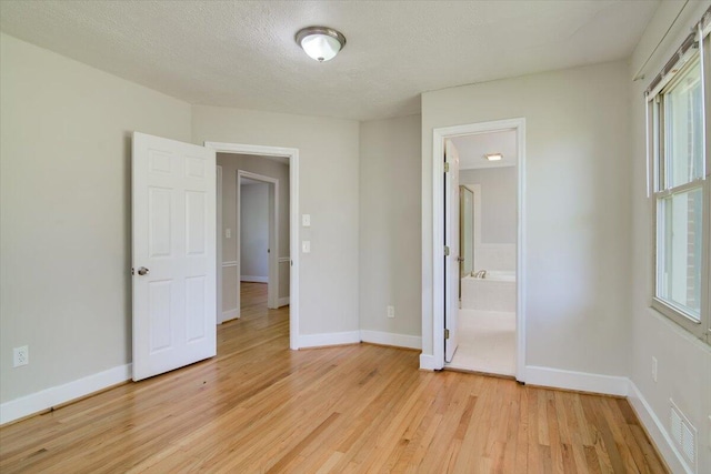 427 Ashland Dr, Augusta, GA 30909 - unfurnished bedroom featuring light wood-type flooring, ensuite bathroom, and a textured ceiling