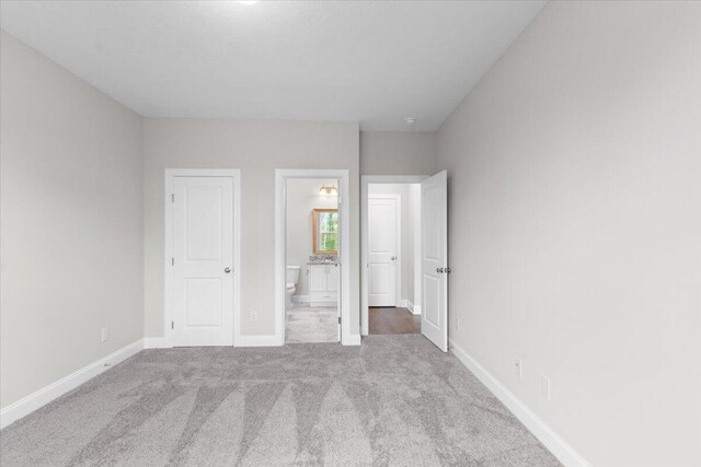 unfurnished bedroom with connected bathroom, carpet, and baseboards