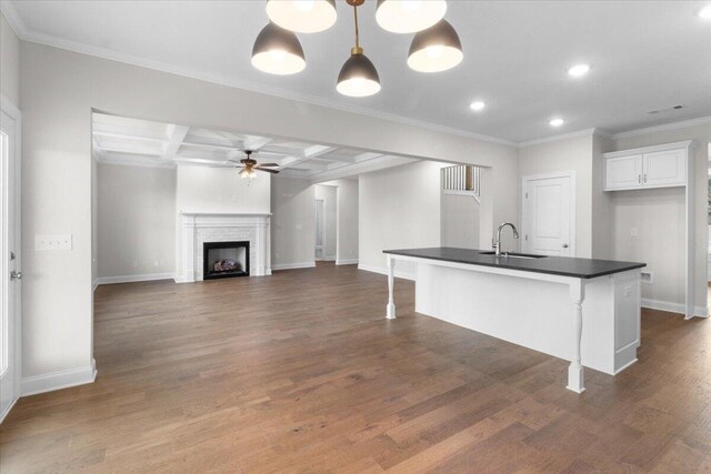 kitchen featuring dark countertops, white cabinets, a sink, ceiling fan, and open floor plan