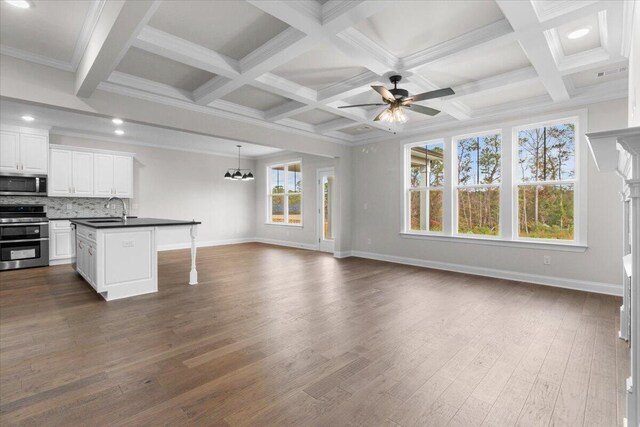 kitchen with appliances with stainless steel finishes, white cabinetry, dark countertops, and open floor plan