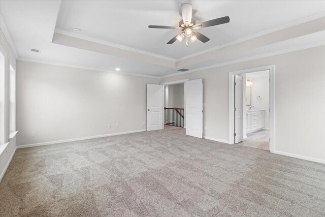 unfurnished bedroom featuring a raised ceiling, baseboards, light colored carpet, and visible vents