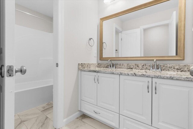 full bathroom with tub / shower combination, double vanity, marble finish floor, and a sink